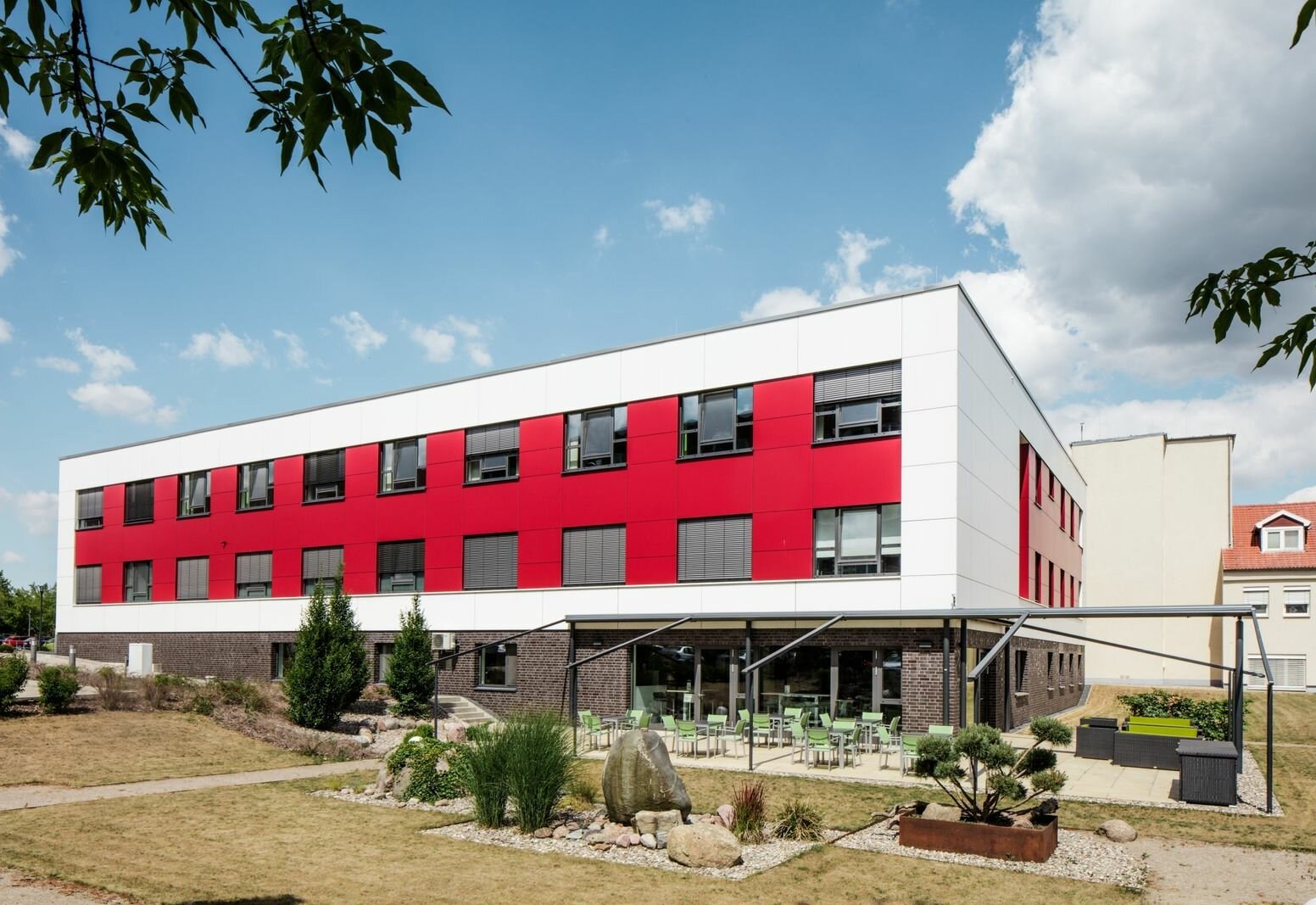 Neubau ITS/IMC und Bettenstation am DRK-Krankenhaus Teterow: weiß-rote Fassade über dem Klinkersockel